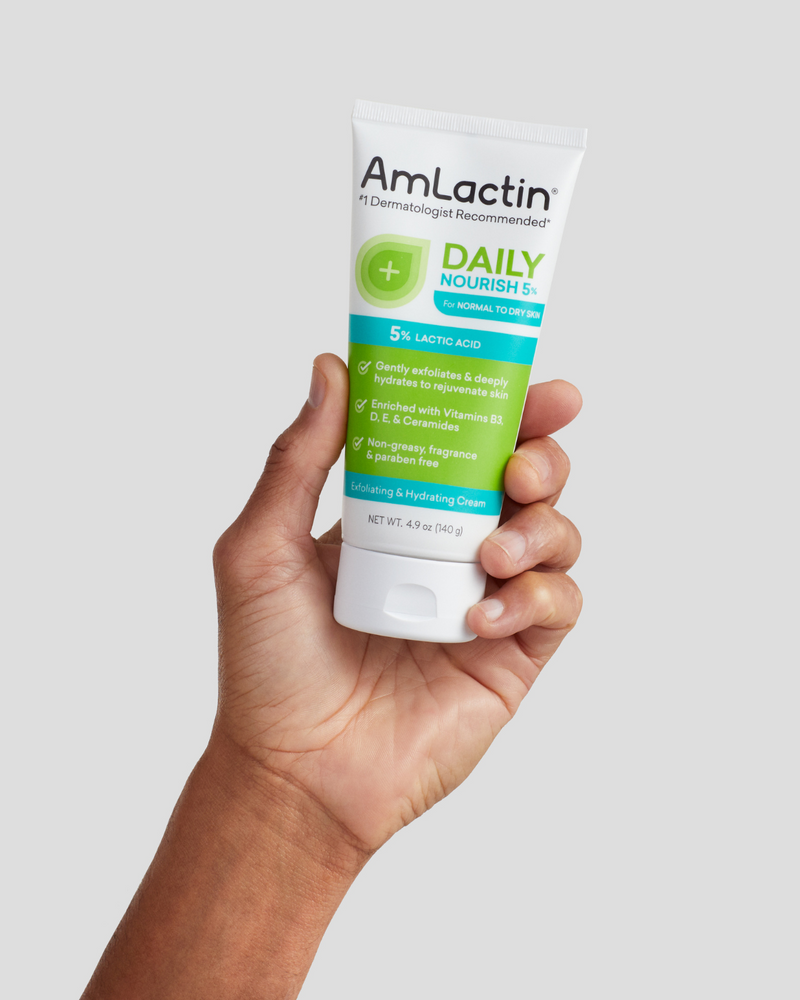 Hand holding AmLactin Daily Nourish 5% Exfoliating and Hydrating Cream 4.9oz tube