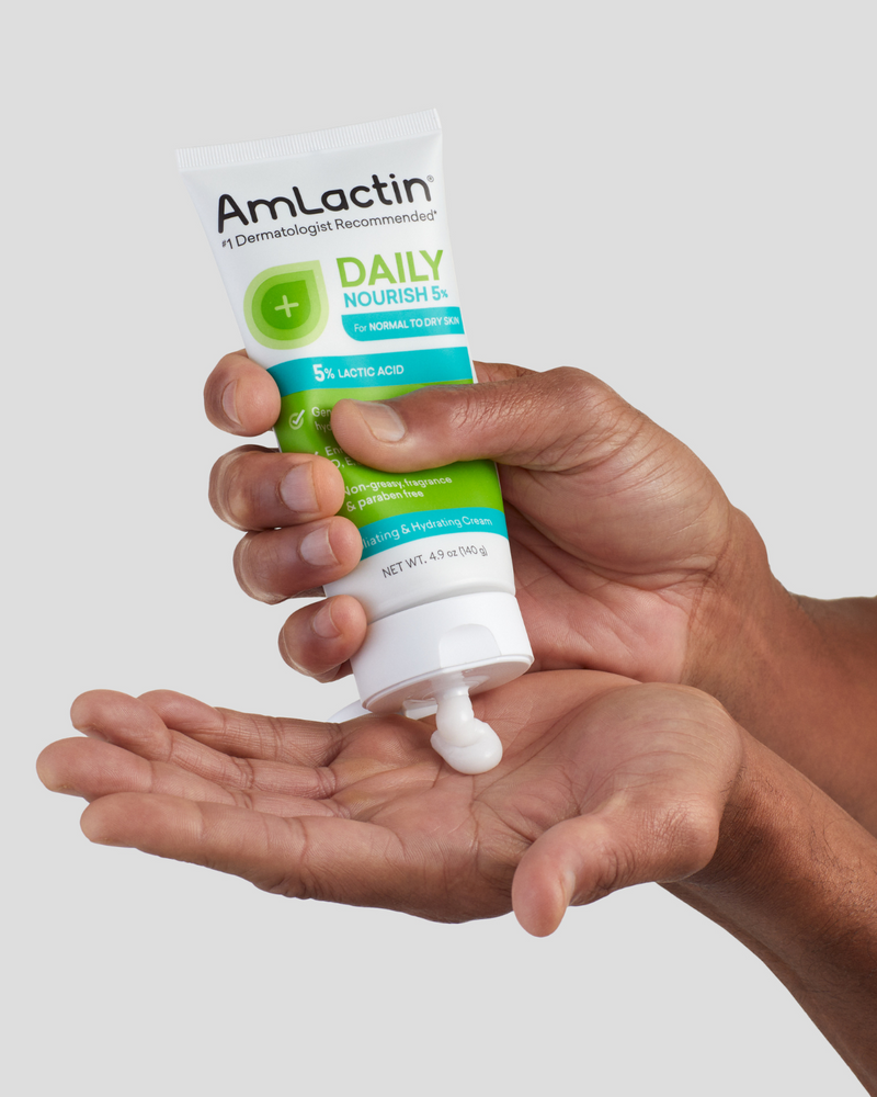 Hand squeezing AmLactin Daily Nourish 5% Cream into the palm of the other hand
