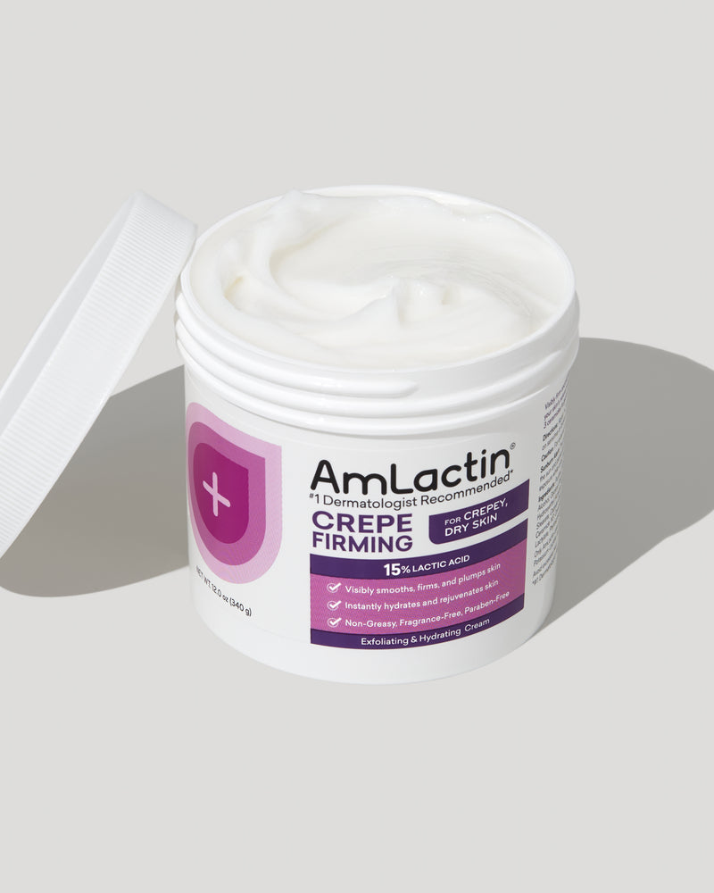 AmLactin Crepe Firming Cream Tub on light grey background. Tub lid is removed and diagonally placed on the side of the tub.