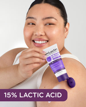 Plus size Asian woman holding AmLactin KP Bumps Be Gone Cream 3 oz Tube over shoulder. Cream swatch on upper arm.15% Lactic Acid callout flag in purple at bottom of image. Woman wearing white tank top on light grey background.