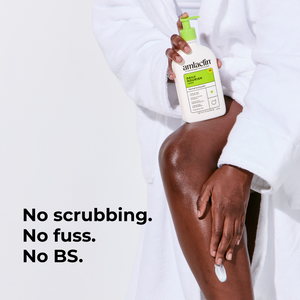A person in a white robe holds a bottle of amlaclin Daily Nourish Cream while applying a white cream to their leg. The text on the left reads 'No scrubbing. No fuss. No BS.