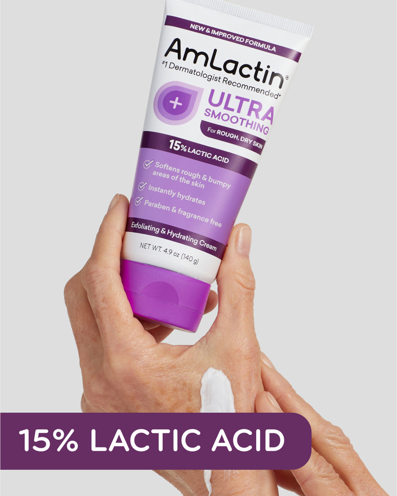Woman's hands holding AmLactin Ultra Smoothing Cream 4.9 oz Tube with light grey background. Cream swatch on hand between thumb and forefinger. 15% Lactic Acid callout flag in purple on bottom of image.
