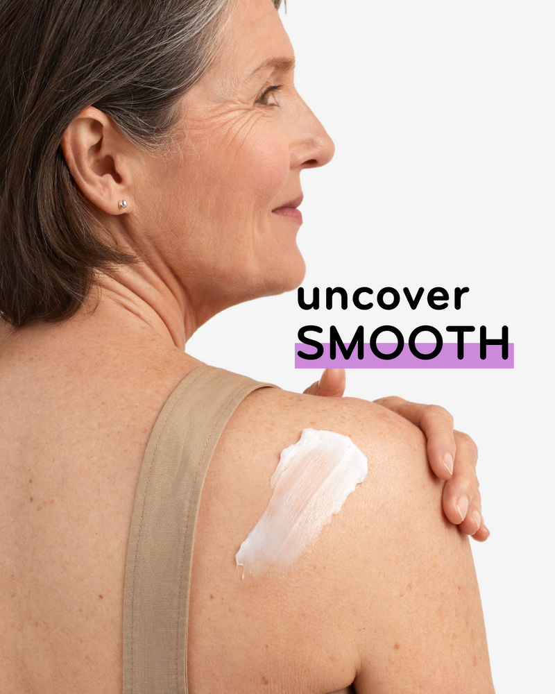 Grey-haired woman with back and shoulder to camera. Cream swatch on her shoulder with copy that says uncover smooth.